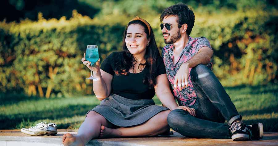 A photo of a couple sitting outside on the grass, chatting