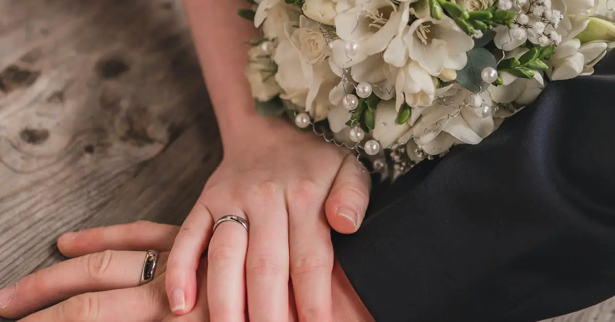 A man and woman holding hands with their wedding/engagement rings on