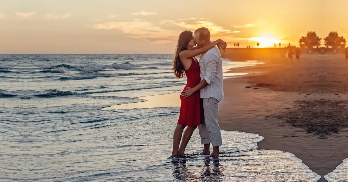 A photo of a loving couple kissing by the shore.