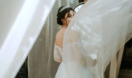 A bride staring at the camera with half of her face covered by a curtain