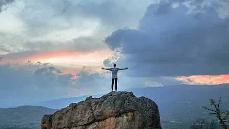 A photo of a man standing on top of a rock