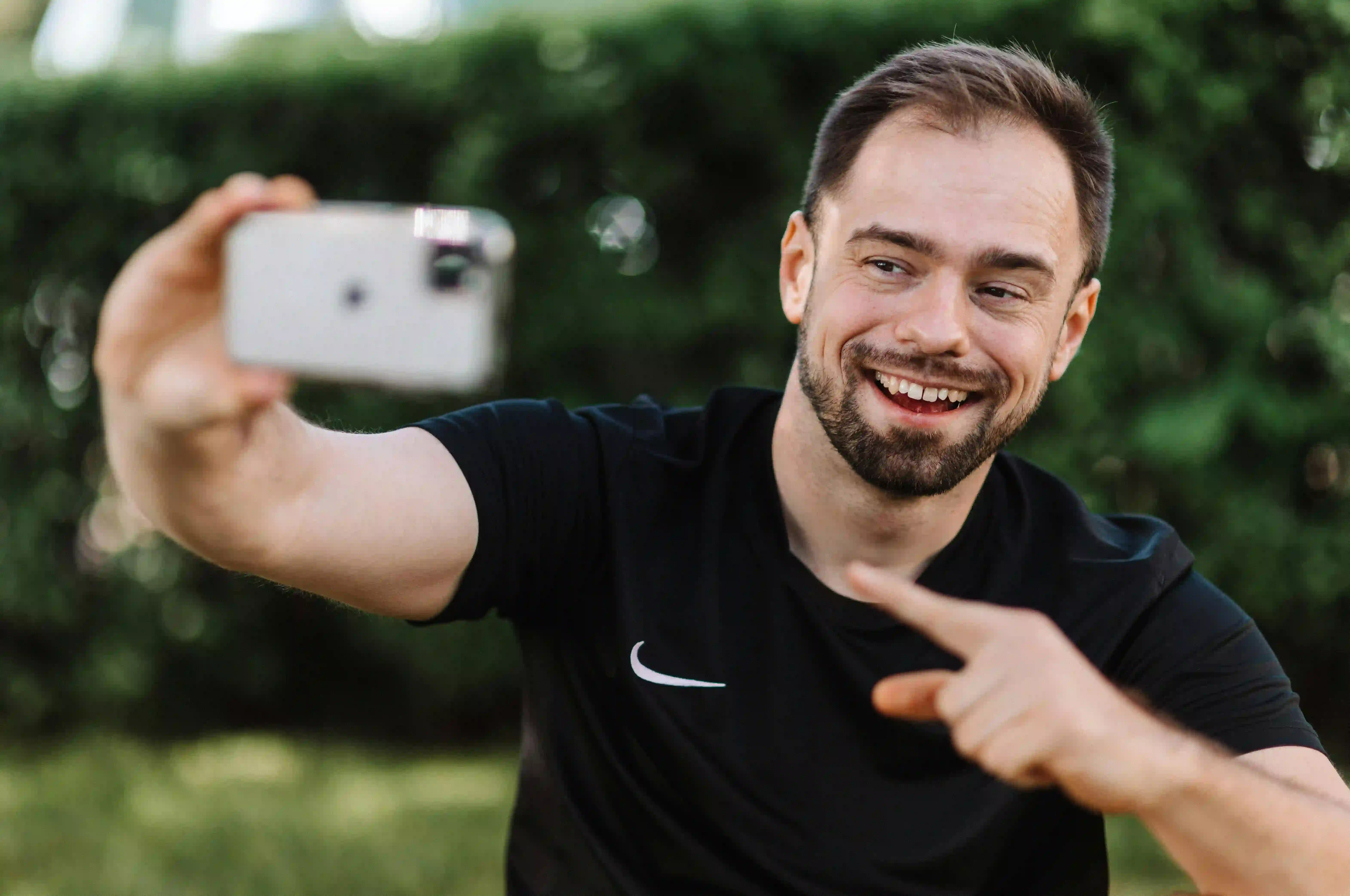 A man in a black shirt taking a selfie with his phone