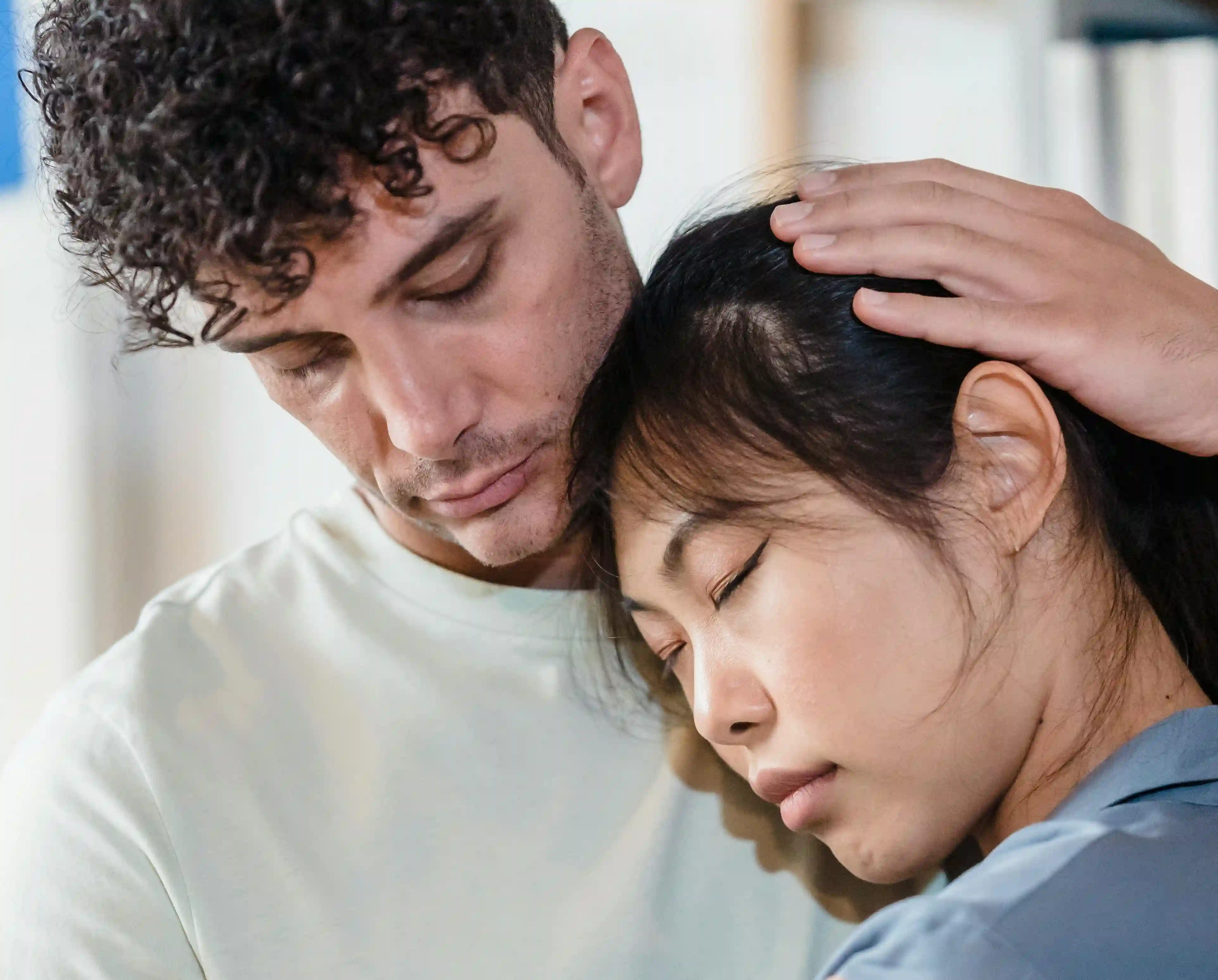A man embracing a woman who has her head on his chest