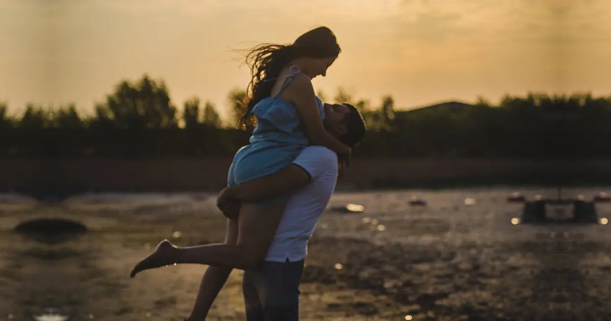 A photo of a man happily carrying a woman in his arms at the beach