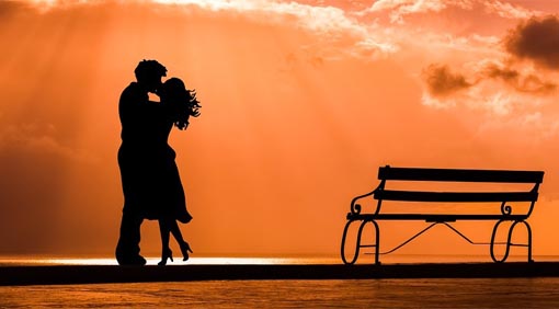 A photo of a couple’s silhouette kissing by the beach.