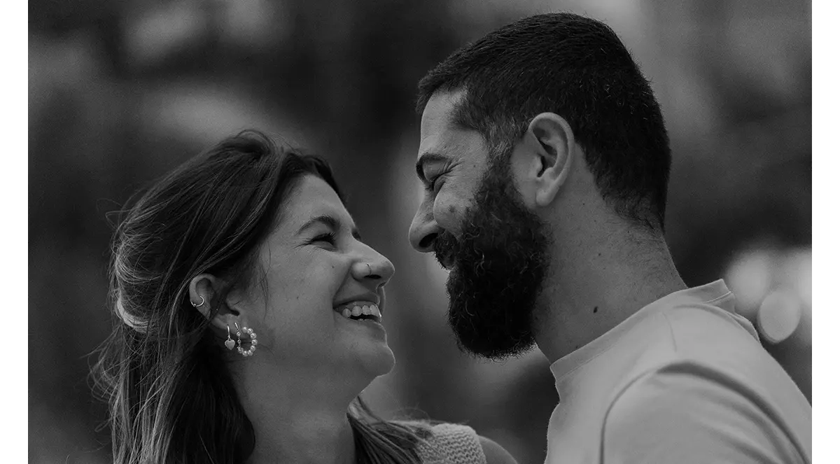 A couple laughing while staring at each other doing the triangle method