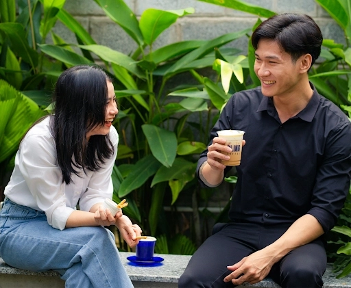 A guy together with a lady who is a yapper sitting on a bench enjoying their time together with coffee