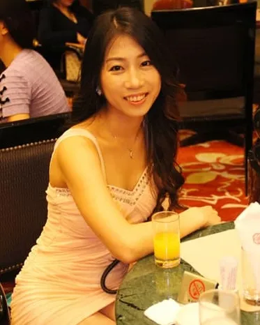 Beautiful Asian woman sitting and leaning on a table, smiling.