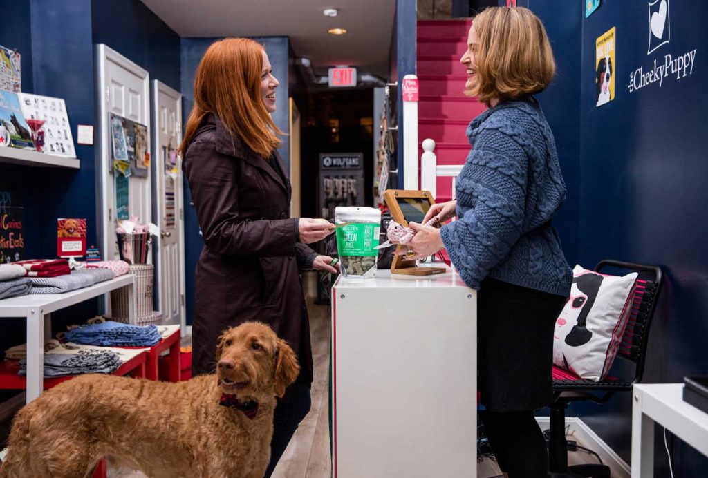 Women with dog talking to merchant in a pet store.