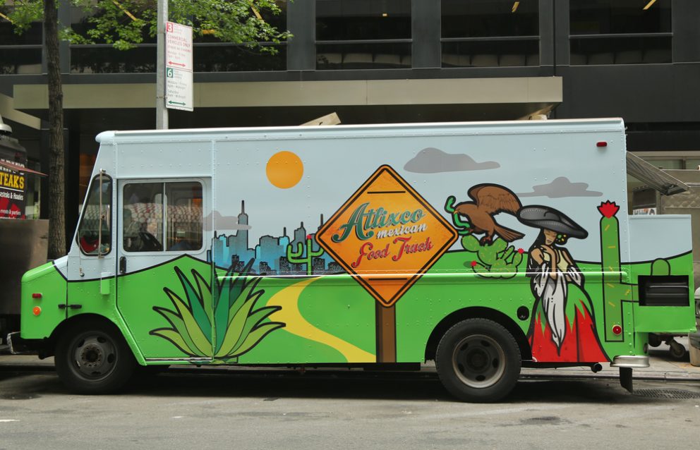 A colorful taco truck parked on the side of the road.