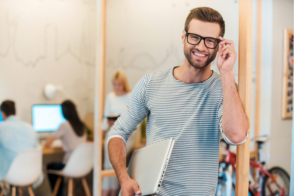 Man carrying laptop and smiling.