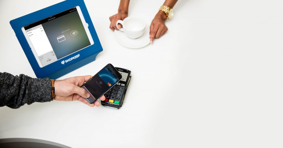 A man using Apple Pay to purchase a cup of coffee.