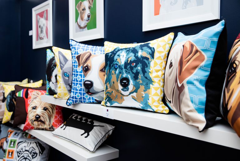Pillows embroidered with dogs displayed on shelves in a pet store.