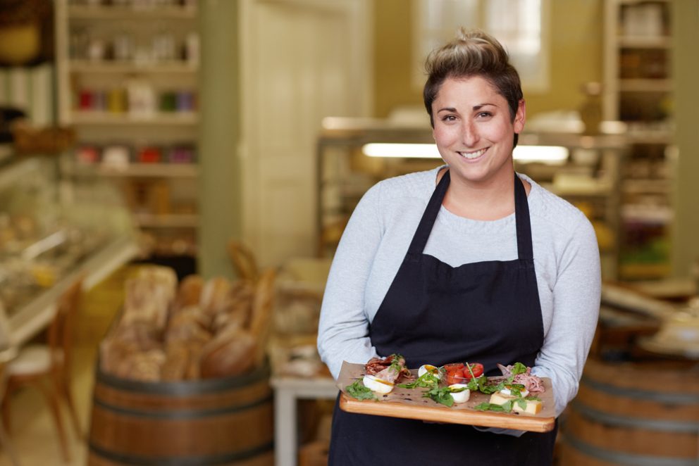 Smiling restaurant employee holding a platter of food.