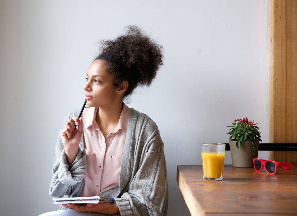 A woman sitting with a pad of paper thinking.