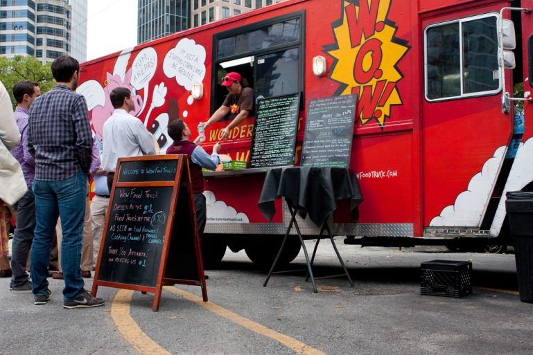 People standing in line in front of a red food truck.