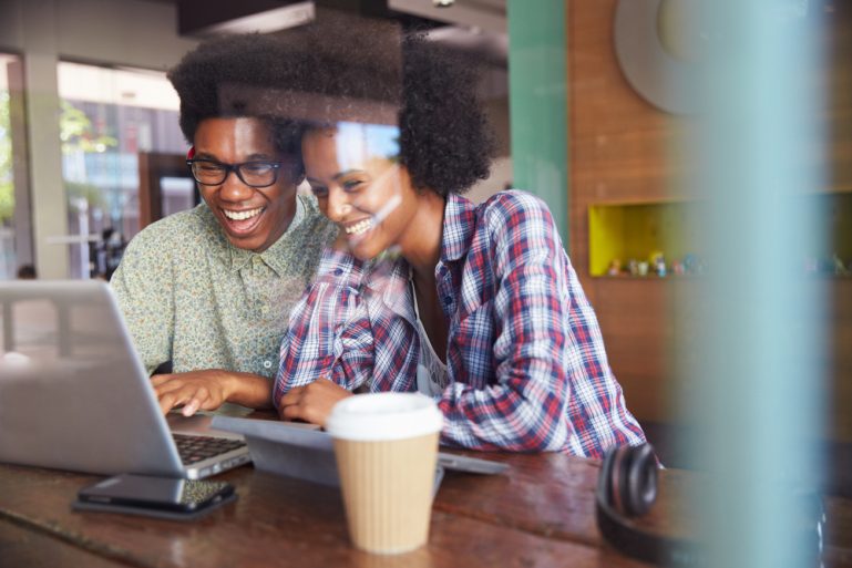 Two people smiling while using ShopKeep and QuickBooks on laptop