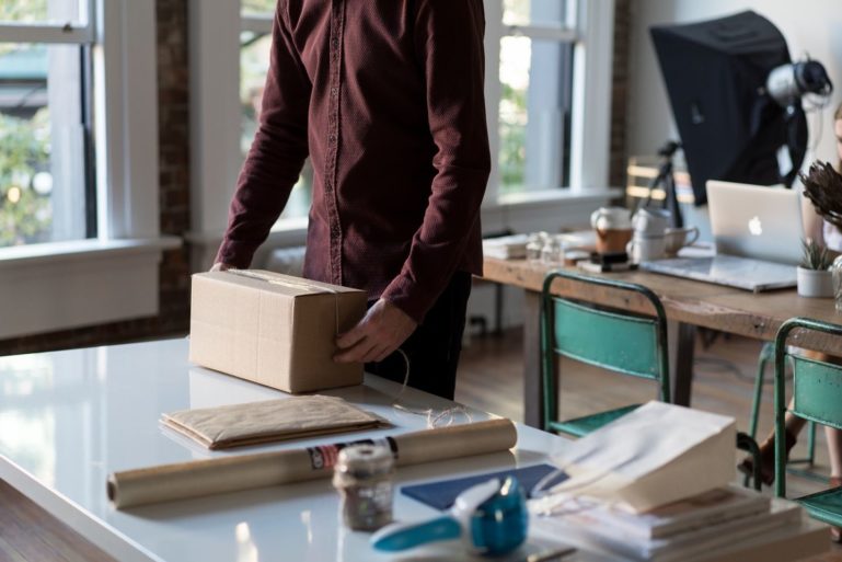 person wrapping brown box - collecting sales tax online