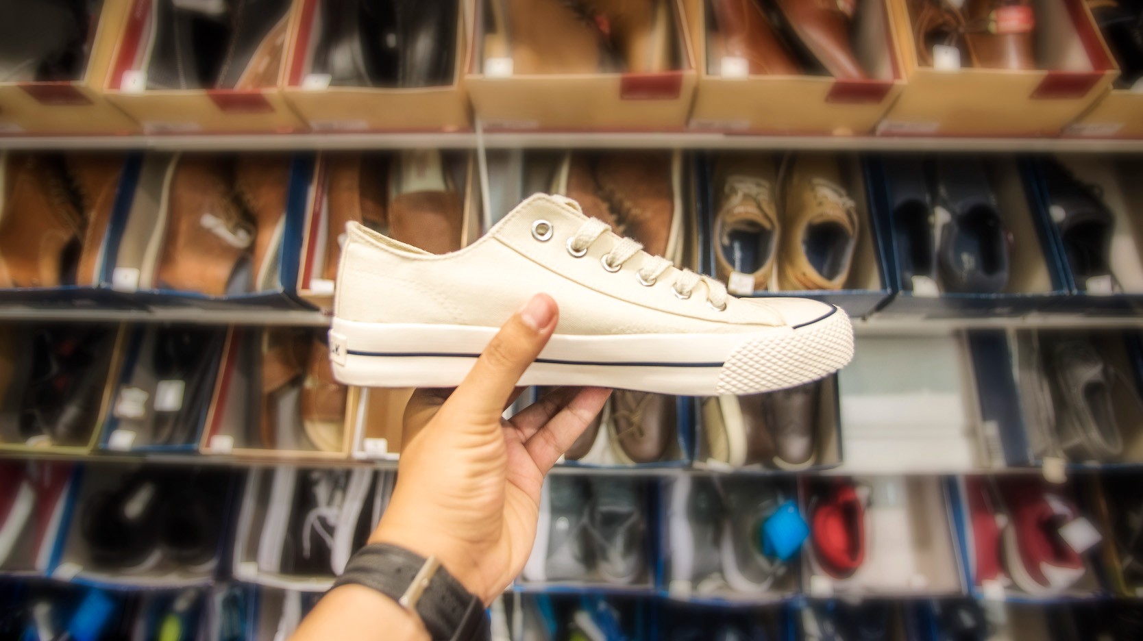 Hand holding sneaker in front of collection