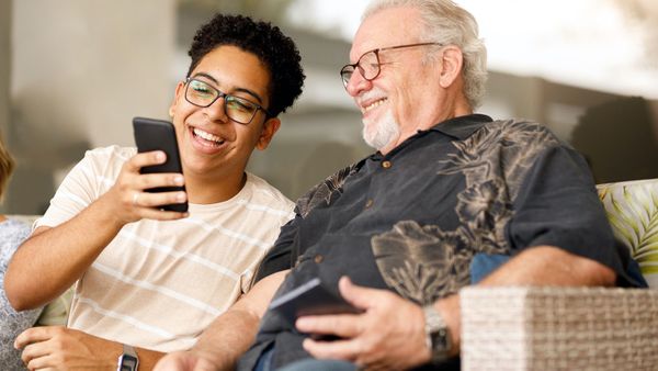 grandson showing grandfather funny meme on phone laughing