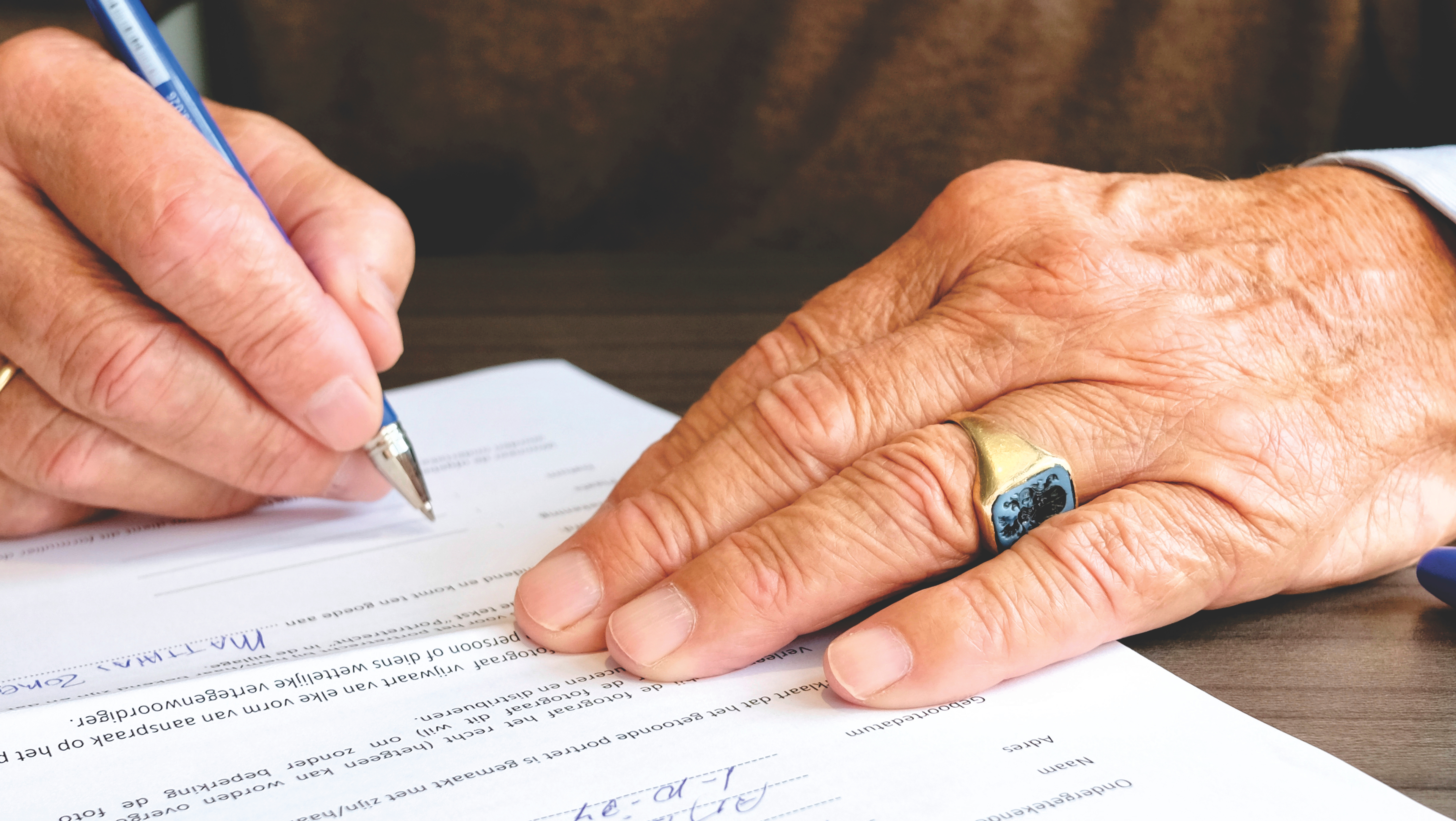 Man signing a document; gift and estate taxes. Photo by Matthias Zomer