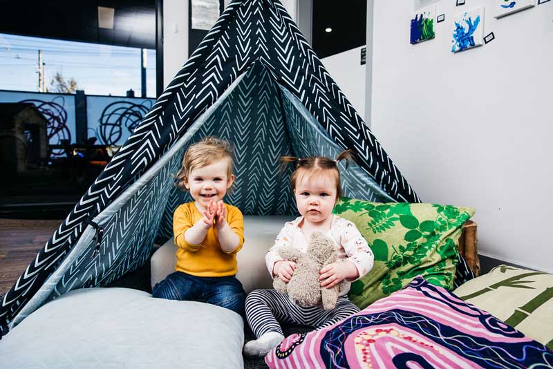 Practise camping with toddlers indoors our out like these two eager children surrounded by pillows.