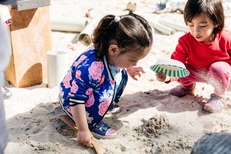 Two children create sand art sculptures.