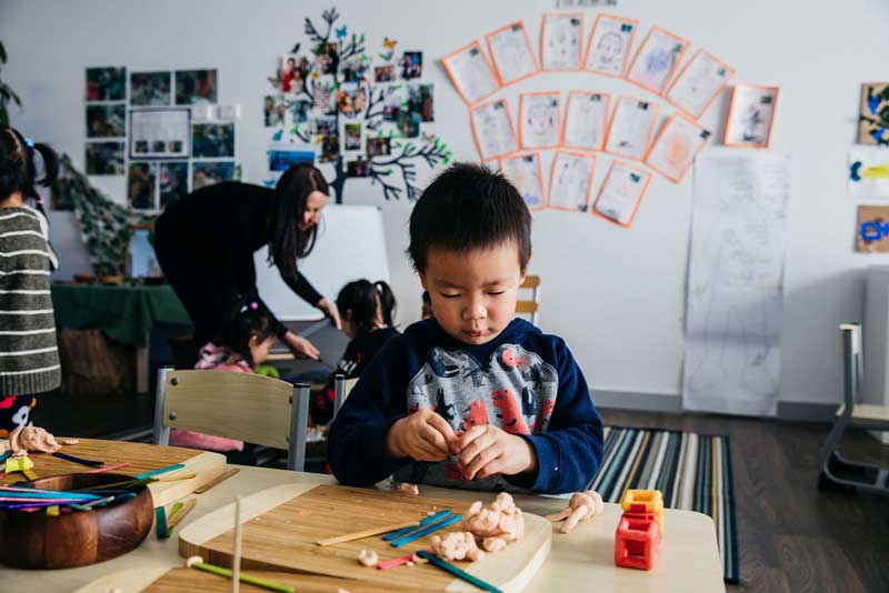 An Early Childhood Teacher prepares focused learning with children playing with clay.