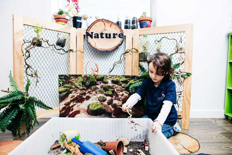 Child plays with a mix of natural resources and toys in a sensory tub.