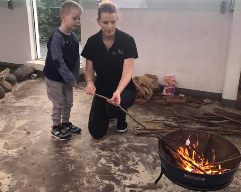 Child and Educator Practises toasting marsh mellows-a fun activity when camping with kids.