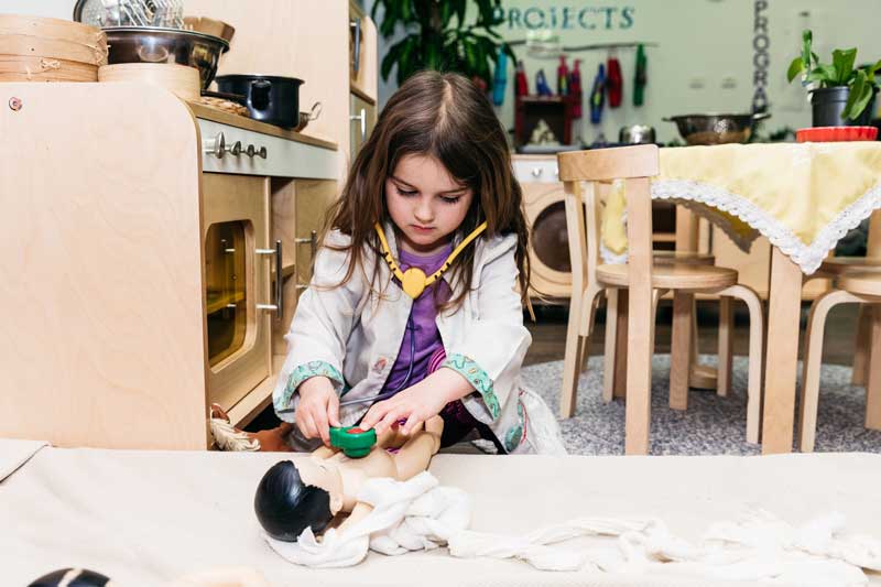 Child roleplays at being a doctor. Roleplaying helps children learn about treating children's burns and other injuries.