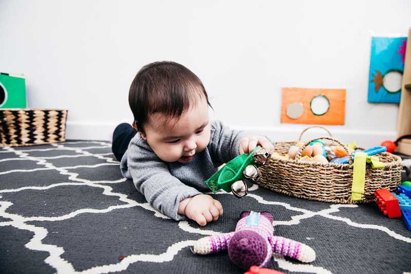 Baby reaches for toys - a 6 month milestone in a baby's development.