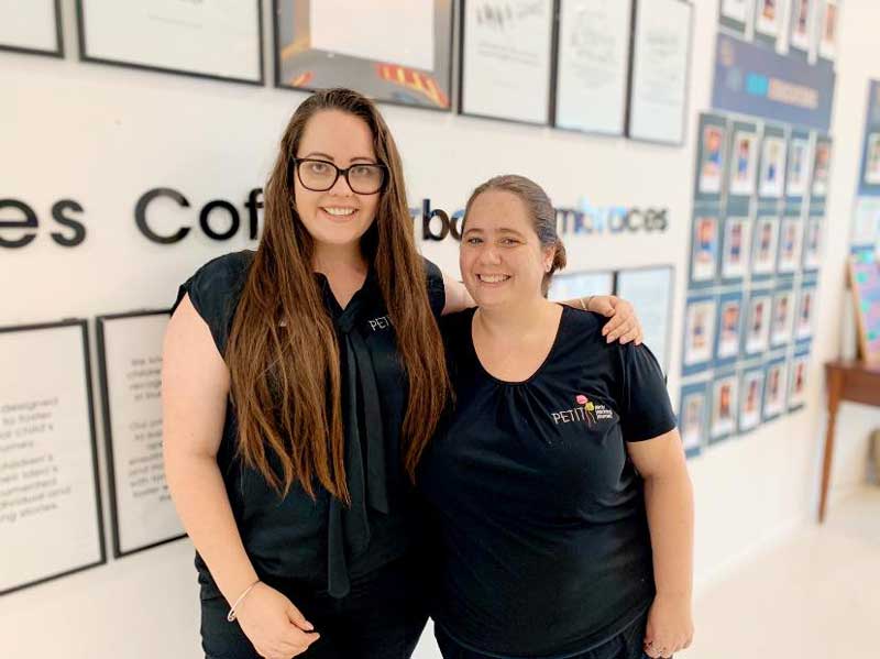 Centre Director stands with a colleague in front of Petit ELJ's philosophy wall.