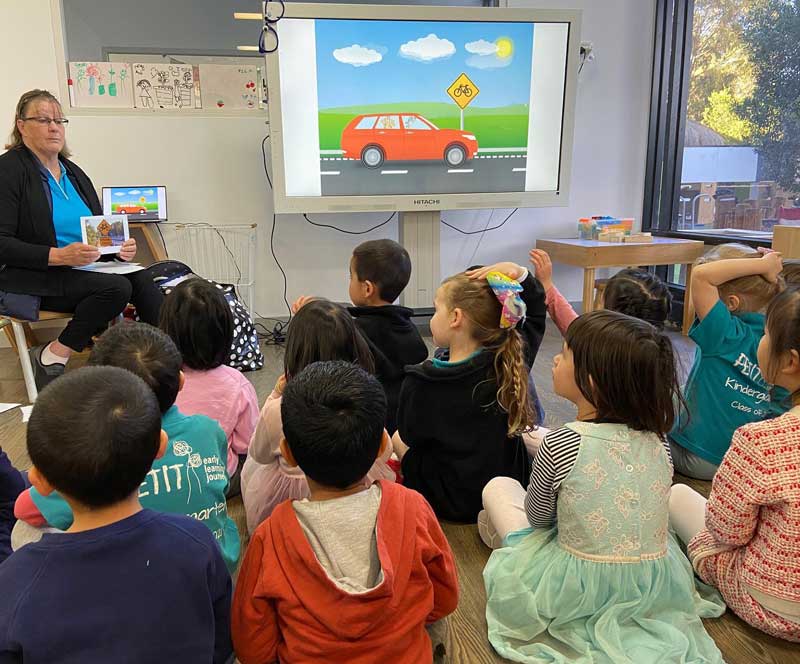Intention teaching at work. Children engage with an educator using flashcards and whiteboard presentation on road safety.