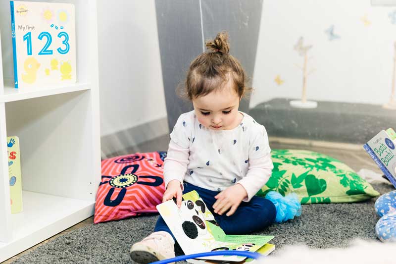 Child looks through a picture book as a pre-writing activity