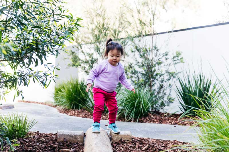 Child balances while walking along a log - a fun physical activity for children.