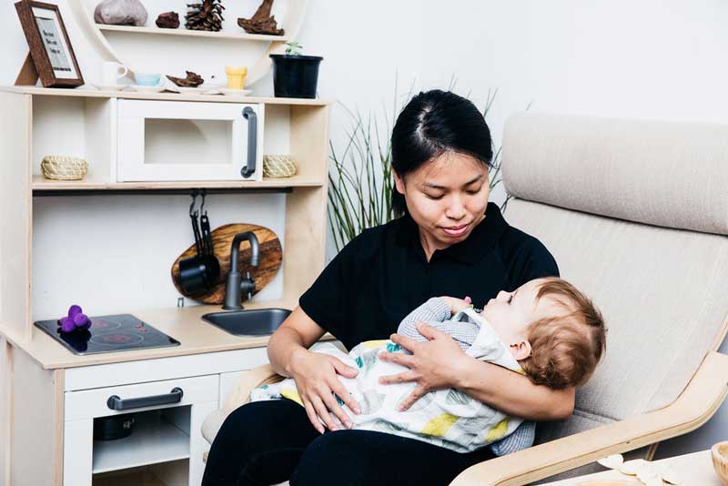 While mum is expressing milk at work, an Educator settles and feeds the baby.