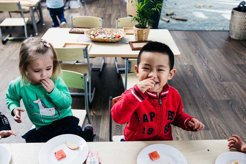 Children use their hands to eat afternoon tea. Self-help skills for 2-year-old children include learning to eat with their fingers and utensils.