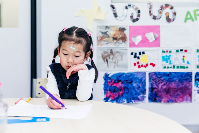 Child draws figures and shapes developing her writing readiness skills .