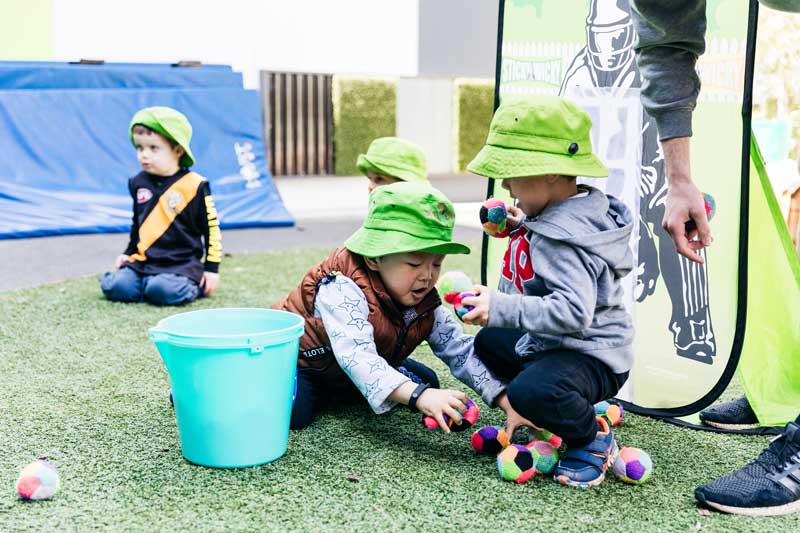 Children pickup balls after playing as part of their cleaning chores.