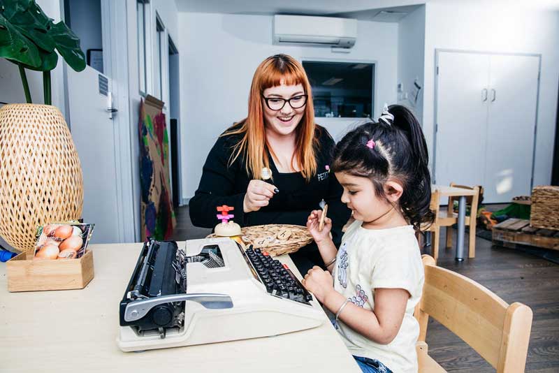 Educator encourages a child to find the letters of her name as a pre-writing skills activity