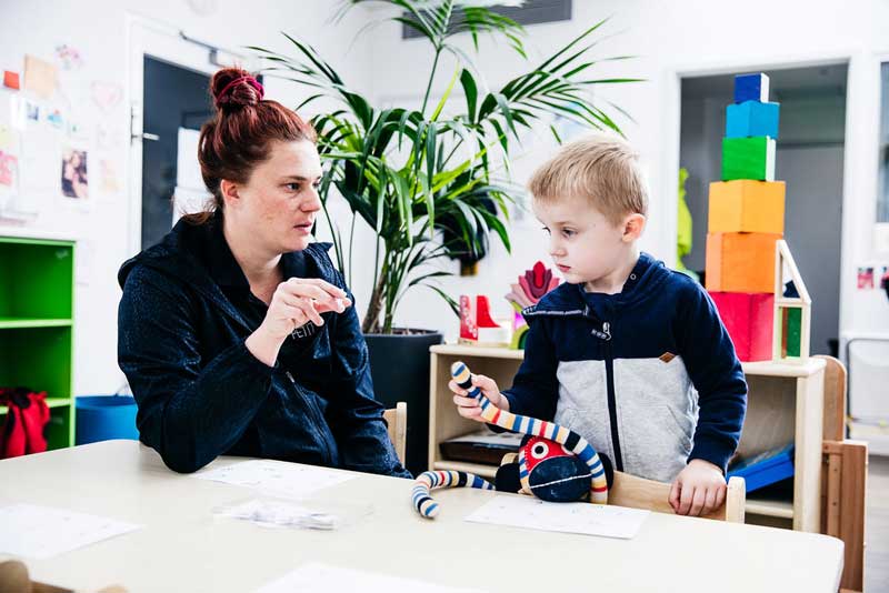 Educator engages child in preschool conversation skills with questions.