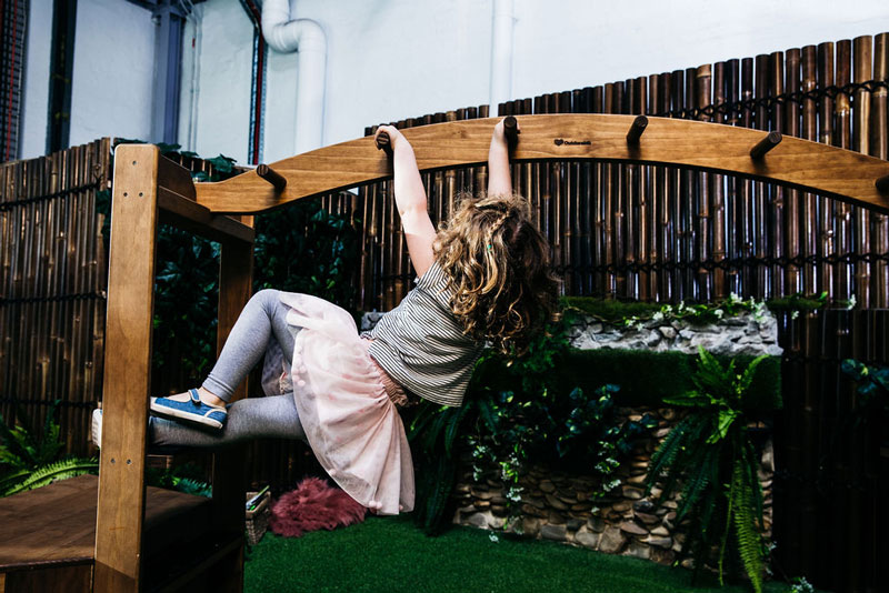 Child uses a monkey bar to strengthen hands and fingers part of pre-writing skills development.