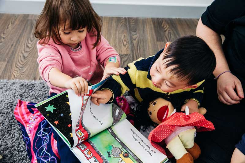 Children play with book mimicking pointing and developing reading skills