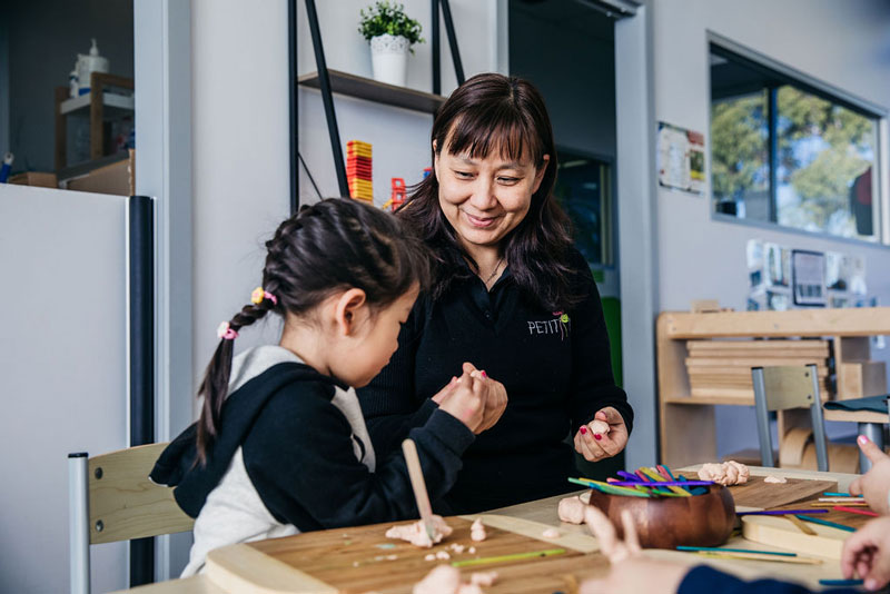 Children use loose parts like craft sticks to make child-made gift ideas.