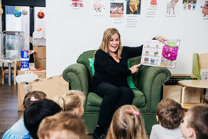 Educator reads to a group of children learning to read.