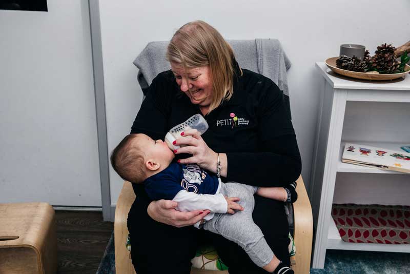 Educator feeds baby with stored milk expressed with a breast pump.