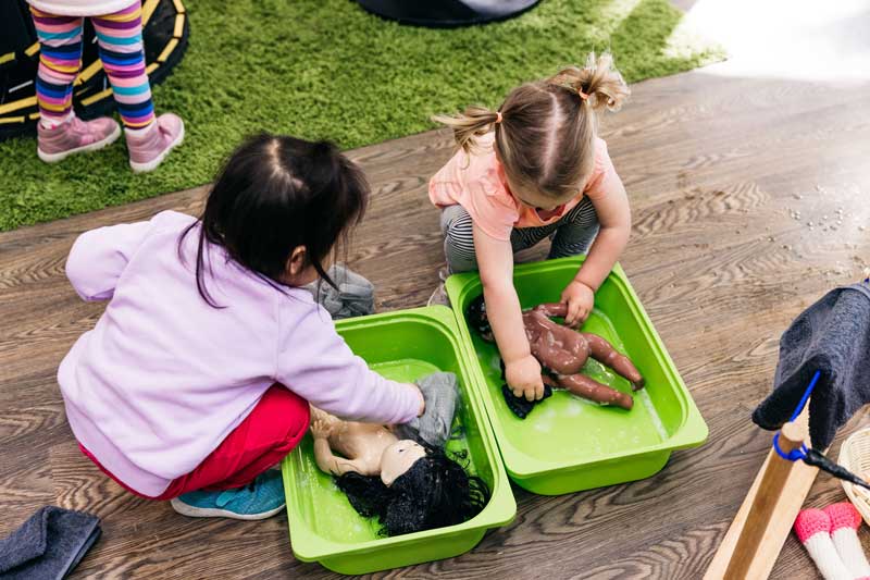 Children play pretend with baby bath toys in a child-led experience.