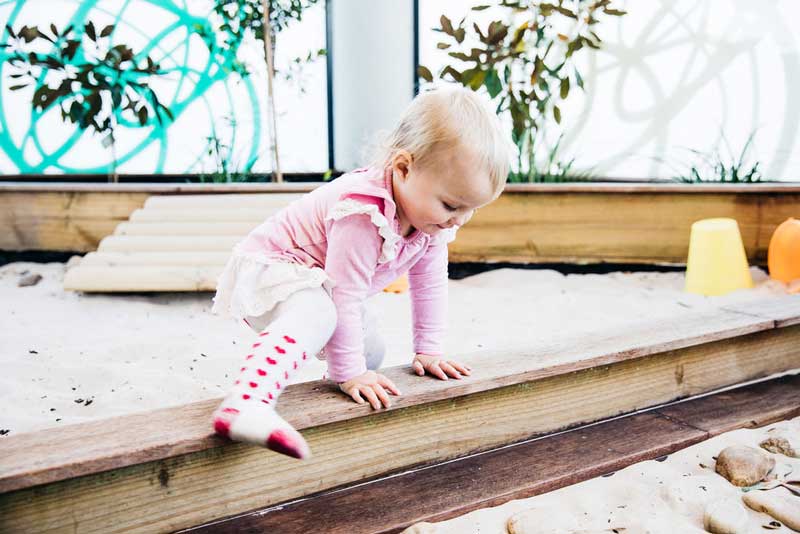 A child learns to climb over things. One of many self-help skills.