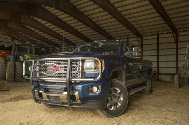 GMC Sierra 3500HD with LUVERNE chrome grille guard in the barn by the tractor